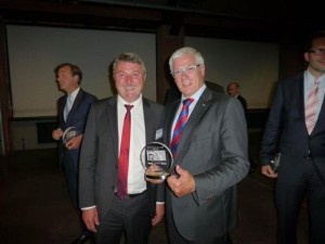 El presidente de Schmitz Cargobull, Ulrich Schöpker (dcha), posa orgulloso con el premio a la mejor marca de semirremolques.